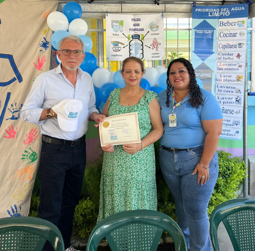 Marisol giving the Agua Viva cap and AVI diploma to Miriam and Manuel